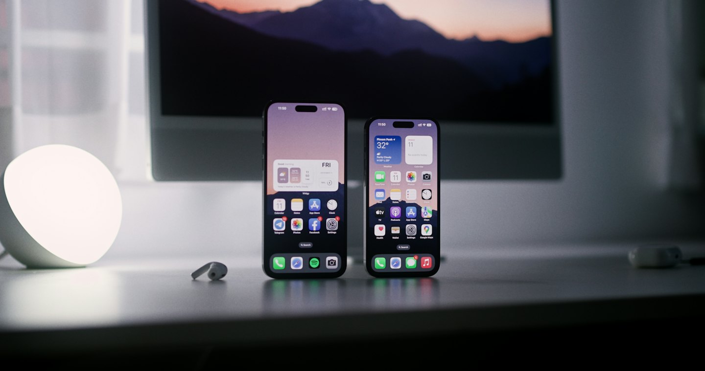 Two smartphones stand upright on a clean white desk.